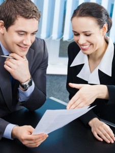 Two happy smiling cheerful young businesspeople working with documents at office